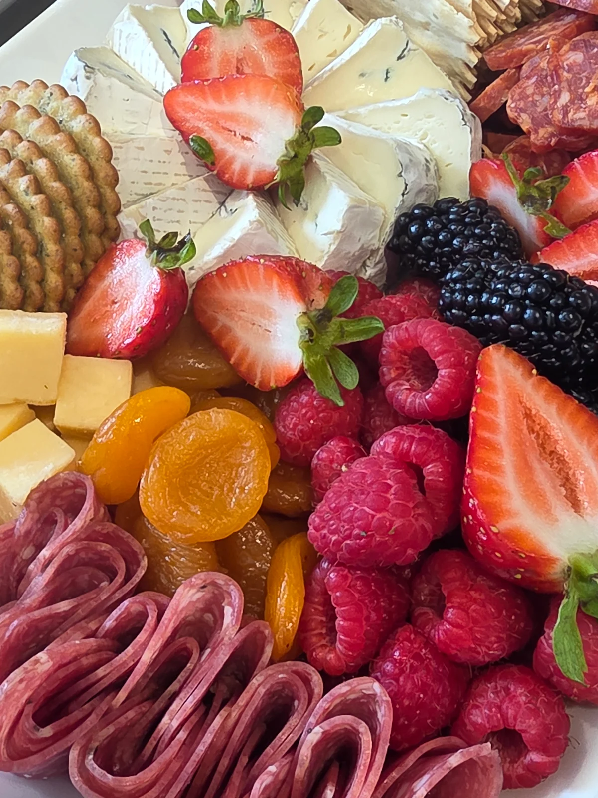 Cheese, berries, crackers, and folded meats ready to share.