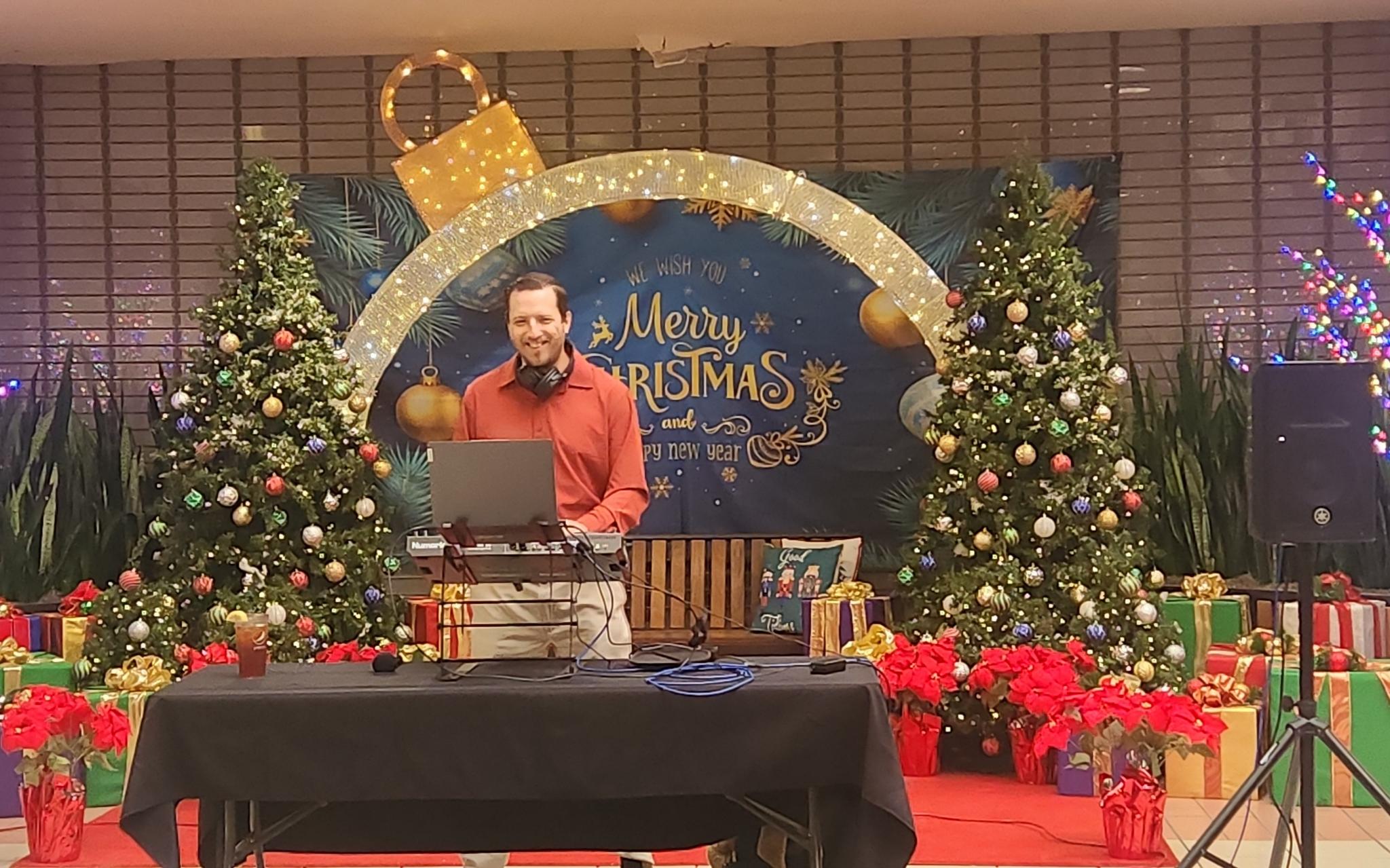 The DJ performing beneath the Merry Christmas arch at Holiday in the Halls